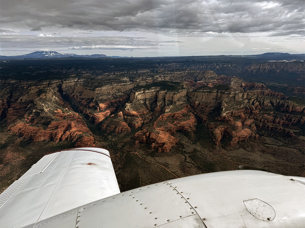 View of an airplane's right wing flying over a mountain range