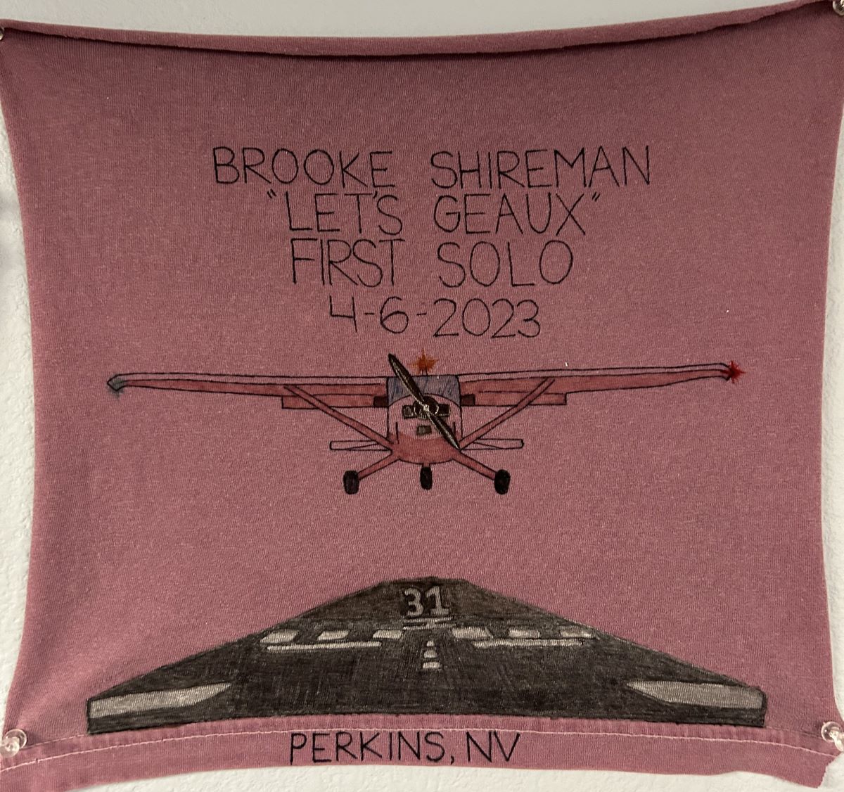 Brooke Shireman's cut shirt with writing representing their first solo flight