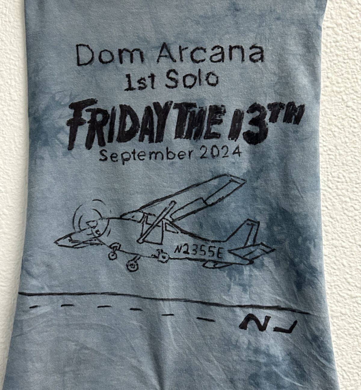 Dom Arcana's cut shirt with writing representing their first solo flight